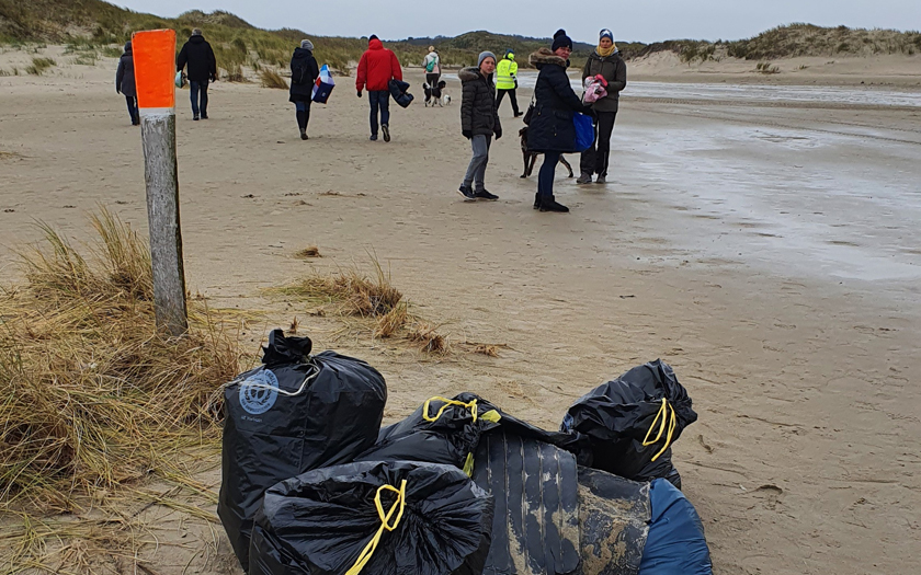 Personen am Strand von Norderney, im Vordergrund mehrere gefüllte Abfallsäcke